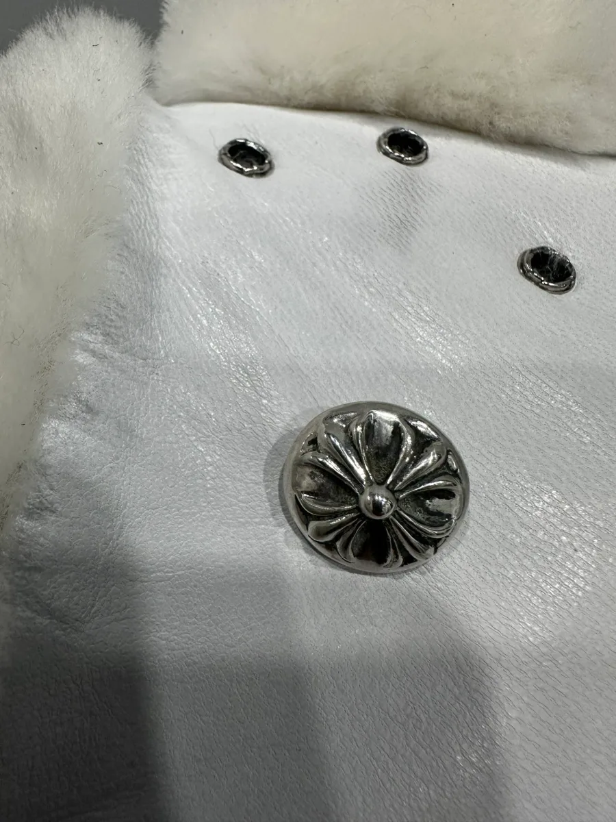 Деталь серебряной фурнитуры Chrome Hearts на белой кожаной шапке