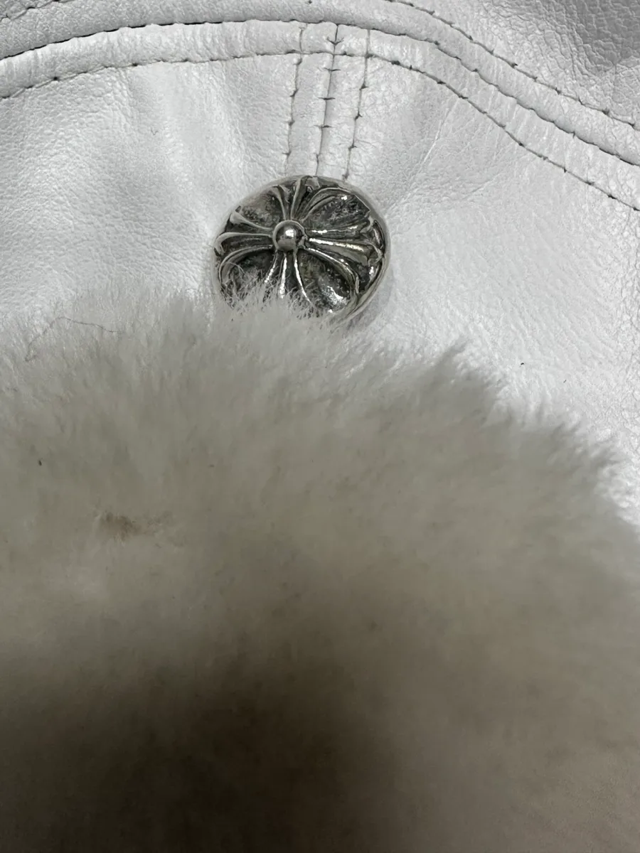 Крупный план серебряной кнопки Chrome Hearts на белом меху