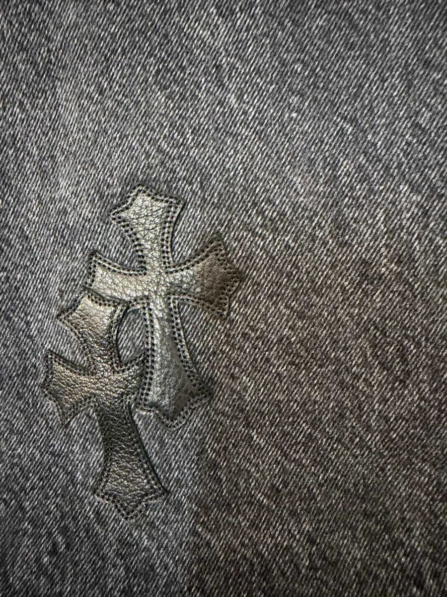 Деталь кожаной нашивки в виде креста на джинсах Chrome Hearts