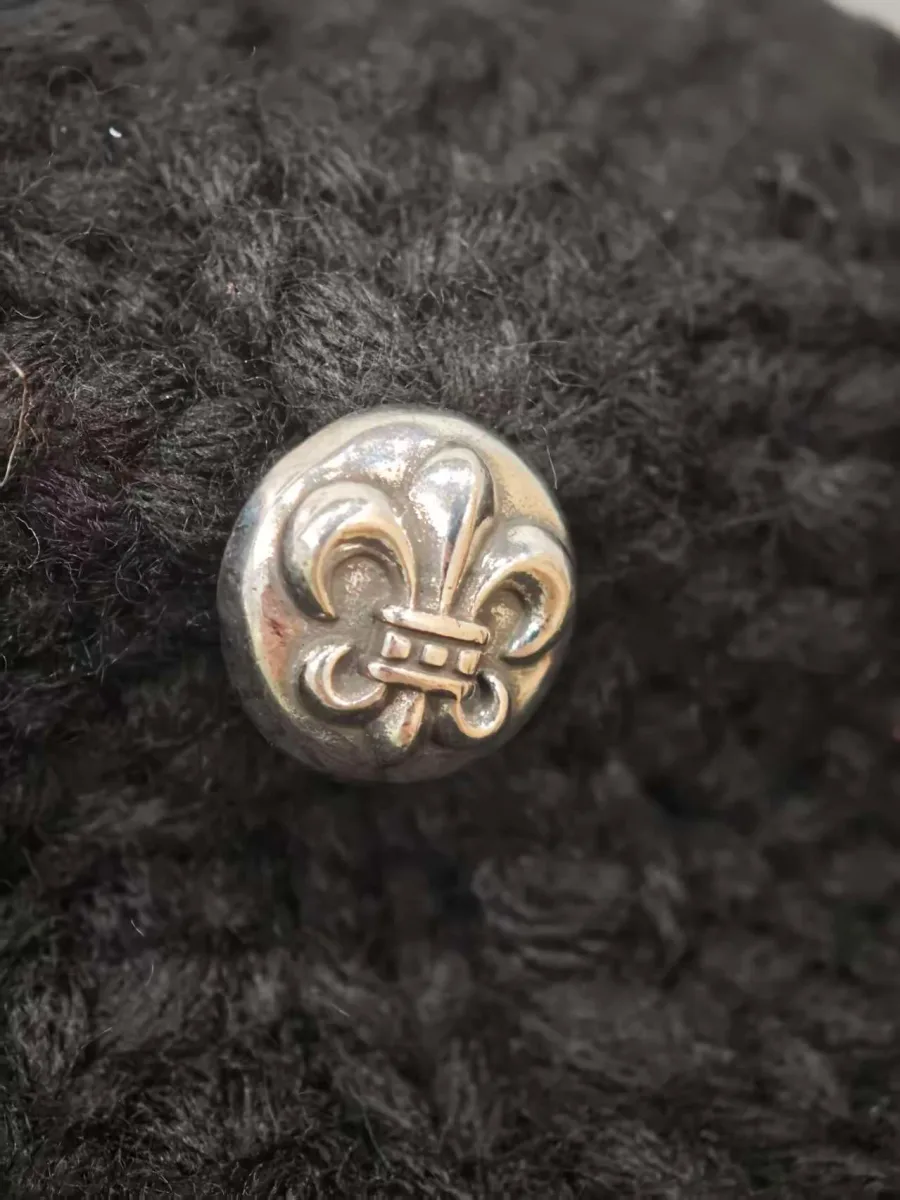 Серебряная кнопка на черной шапке Chrome Hearts крупным планом