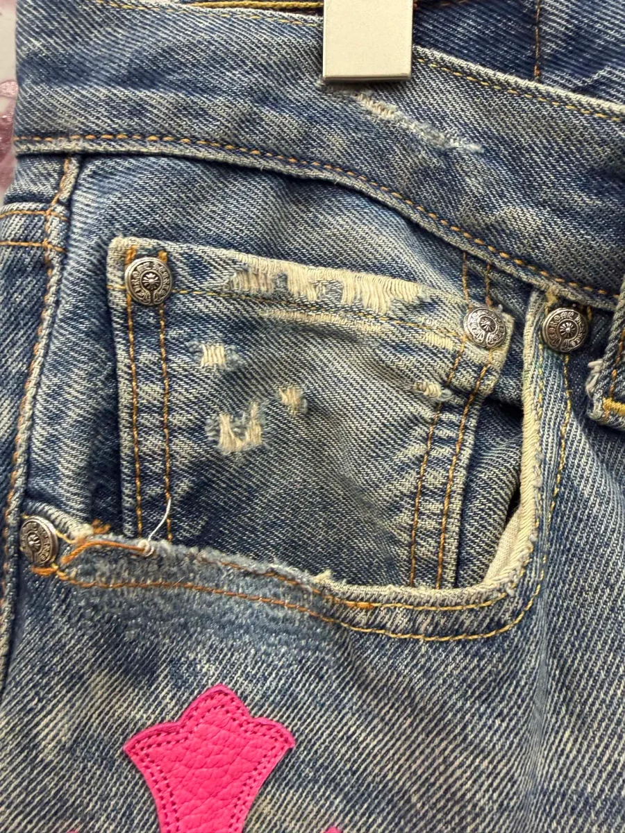 Деталь переднего кармана джинсов Chrome Hearts x Levi's с потертостями и розовой нашивкой