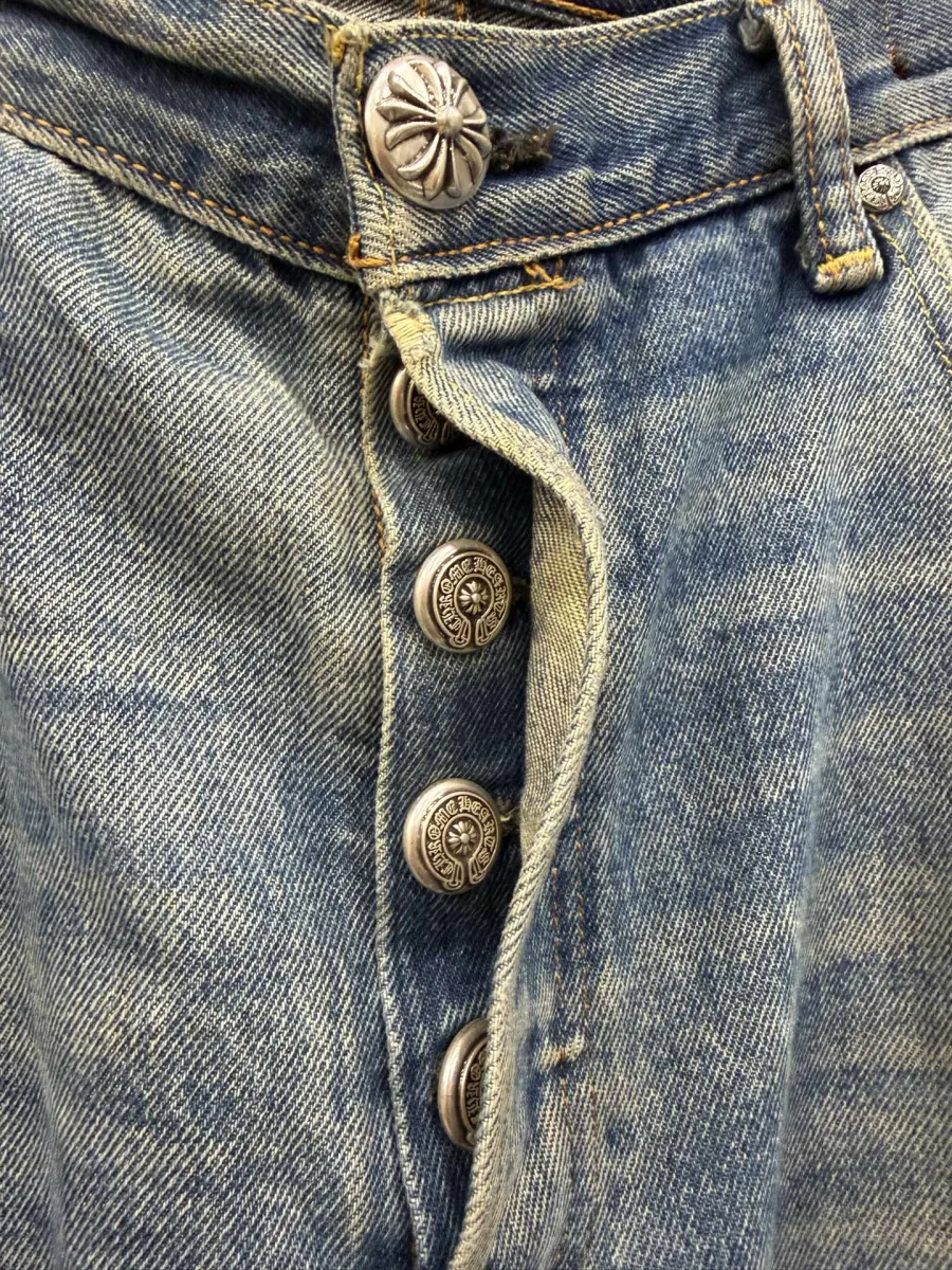 Крупный план серебряных пуговиц-болтов на ширинке джинсов Chrome Hearts x Levi's