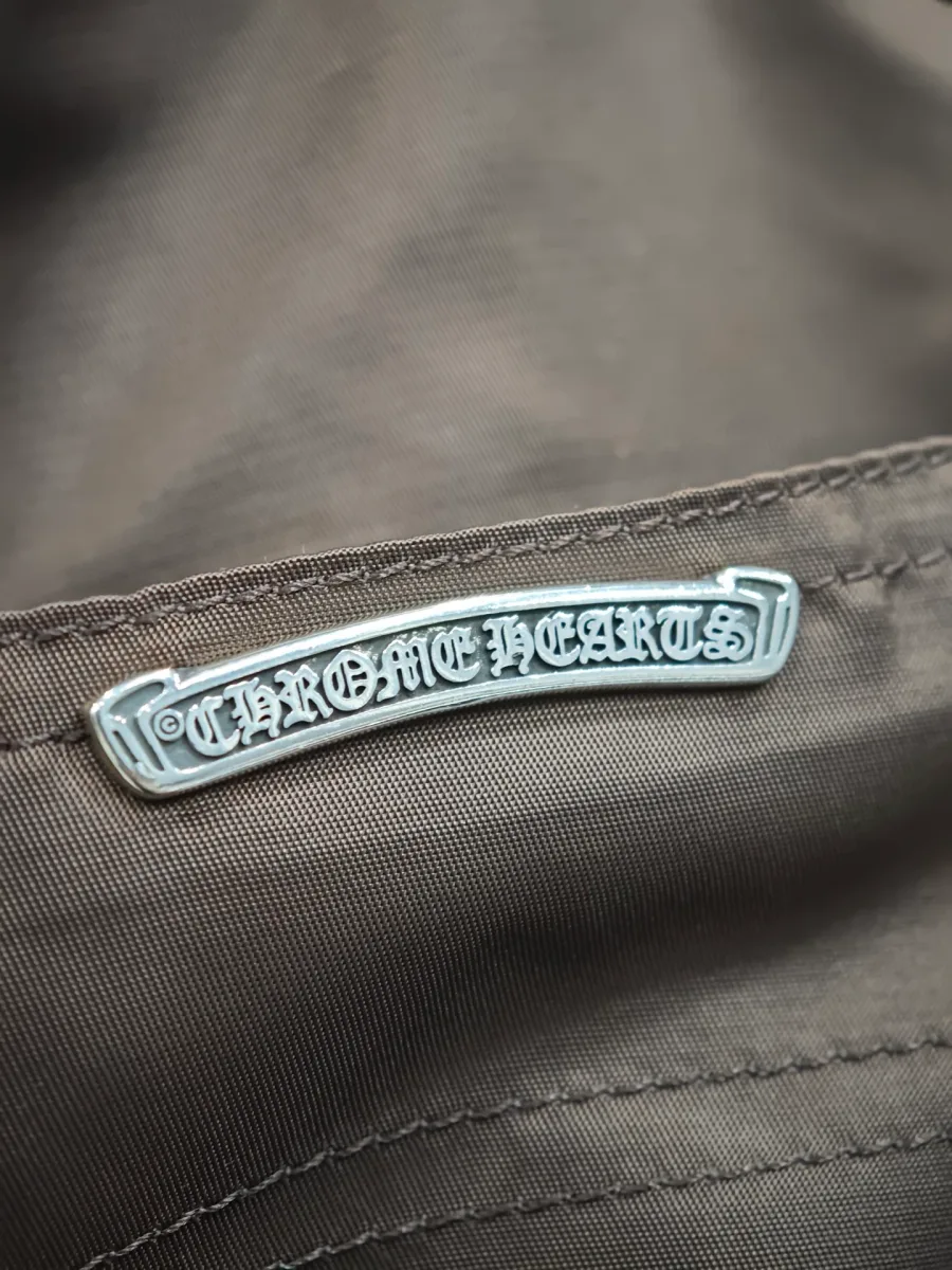 Серебряная пластина с логотипом Chrome Hearts на коричневой ткани