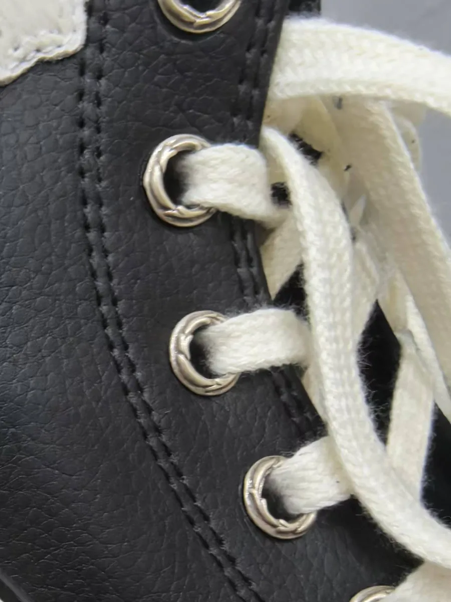 Крупный план кожаной текстуры и металлических люверсов кед Chrome Hearts x Converse