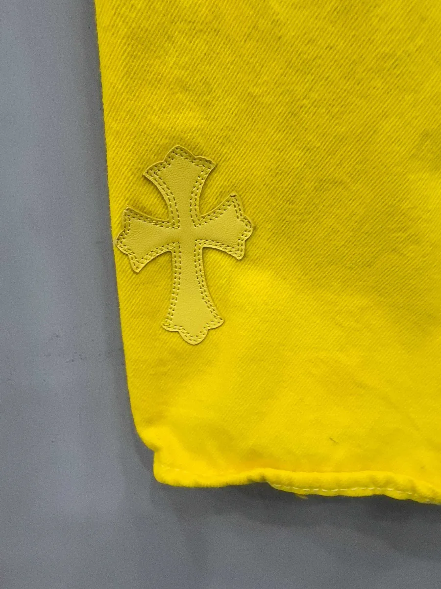 Нижняя часть штанины желтых джинсов Chrome Hearts x Levi's Vintage 501 с нашивкой-крестом