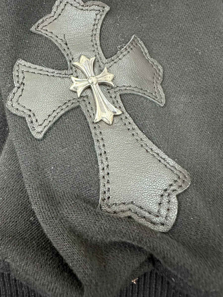 Крупный план кожаной нашивки-креста на рукаве худи Chrome Hearts