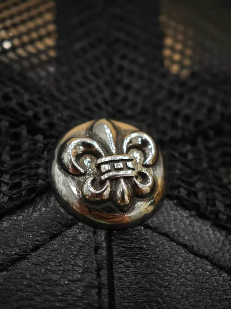 Металлическая деталь в виде лилии на кепке Chrome Hearts
