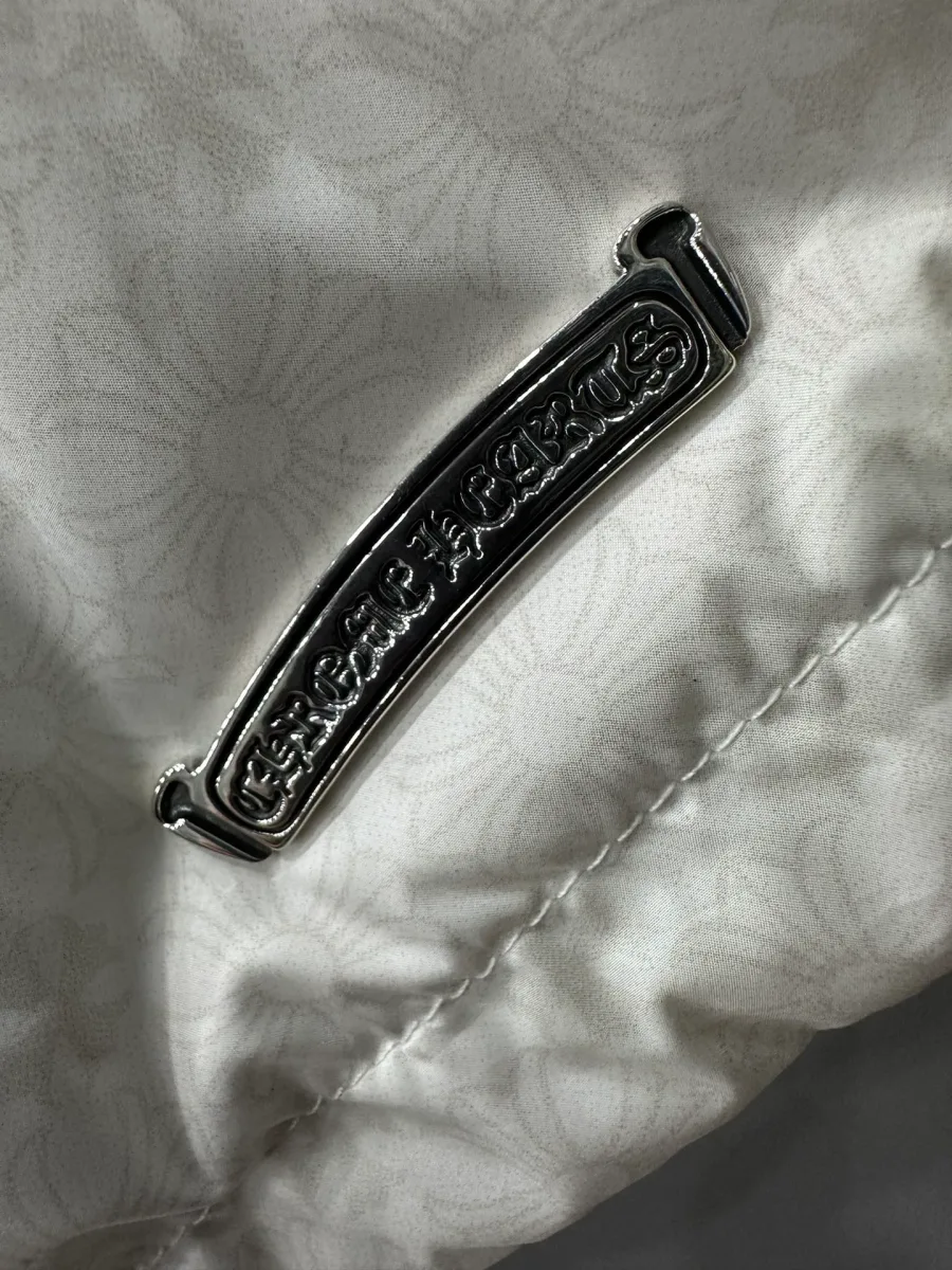 Деталь пуховика Chrome Hearts: серебряная нашивка с логотипом бренда
