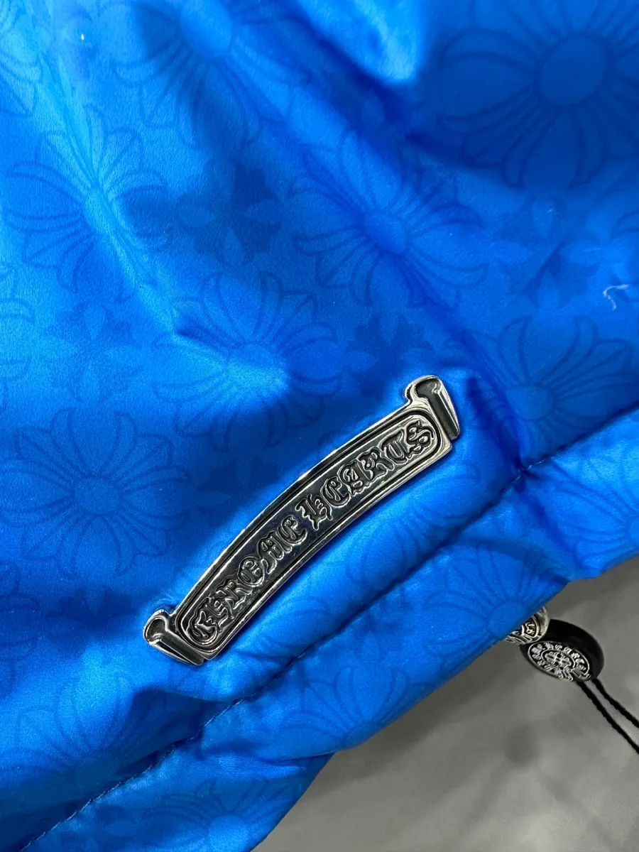 Деталь синего пуховика Chrome Hearts: серебряная нашивка с логотипом бренда