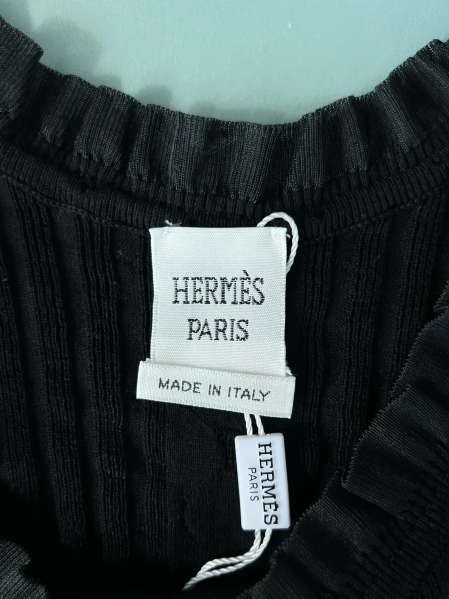 Внутренний ярлык бренда Hermès Paris на горловине чёрного топа, крупный план