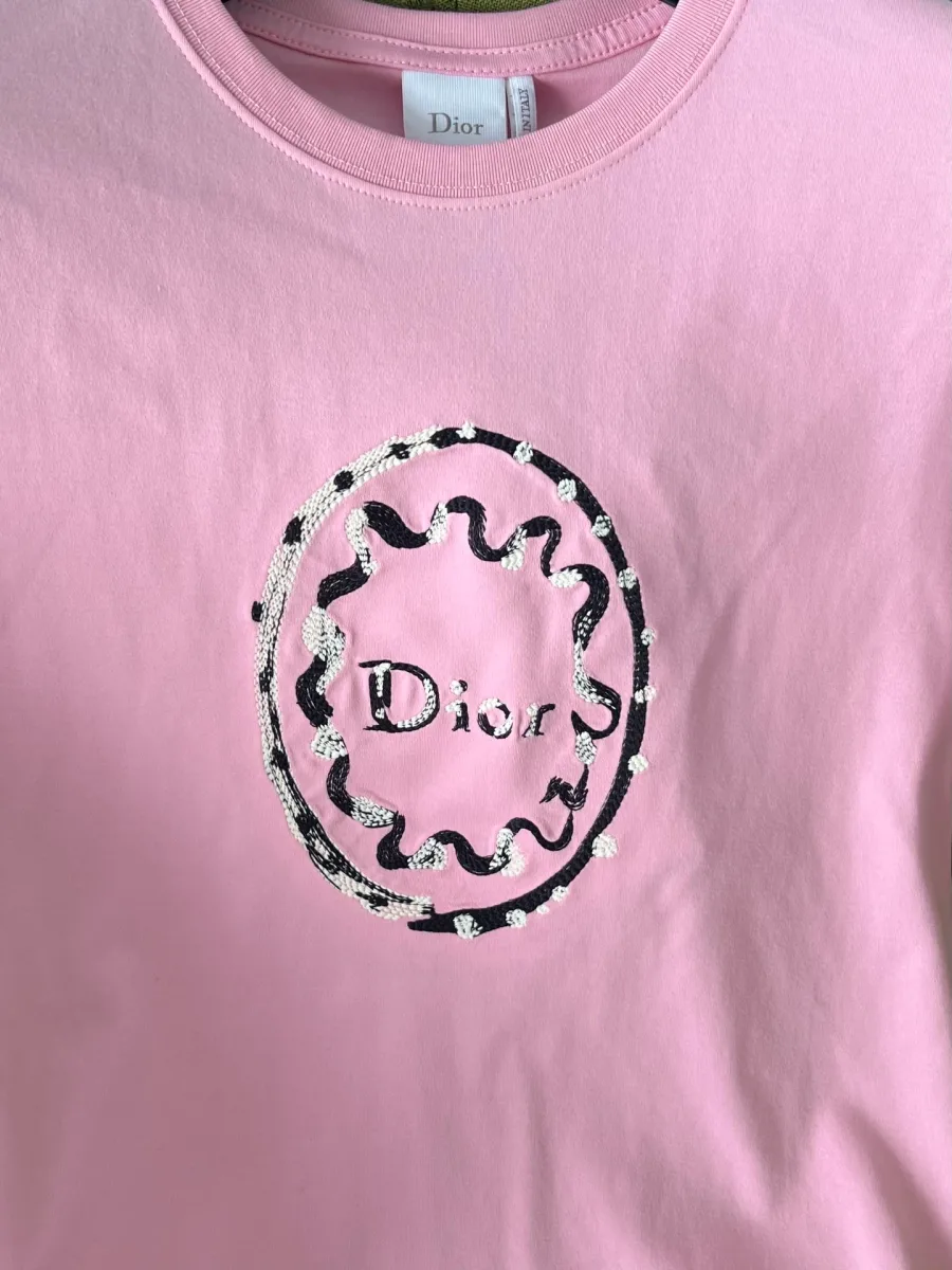 Фактурный овальный медальон с вышитым логотипом Dior на груди крупным планом