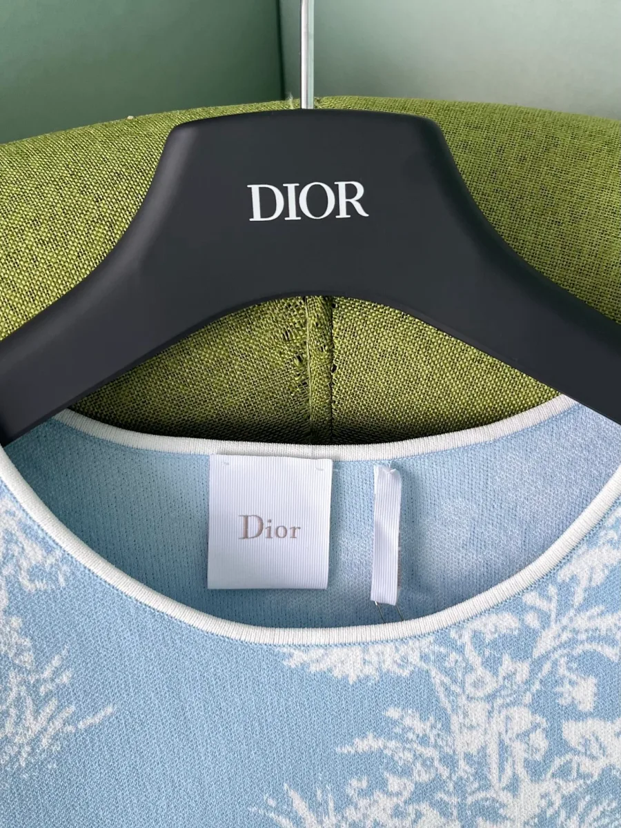 Круглый вырез голубой футболки с биркой Dior и белой окантовкой