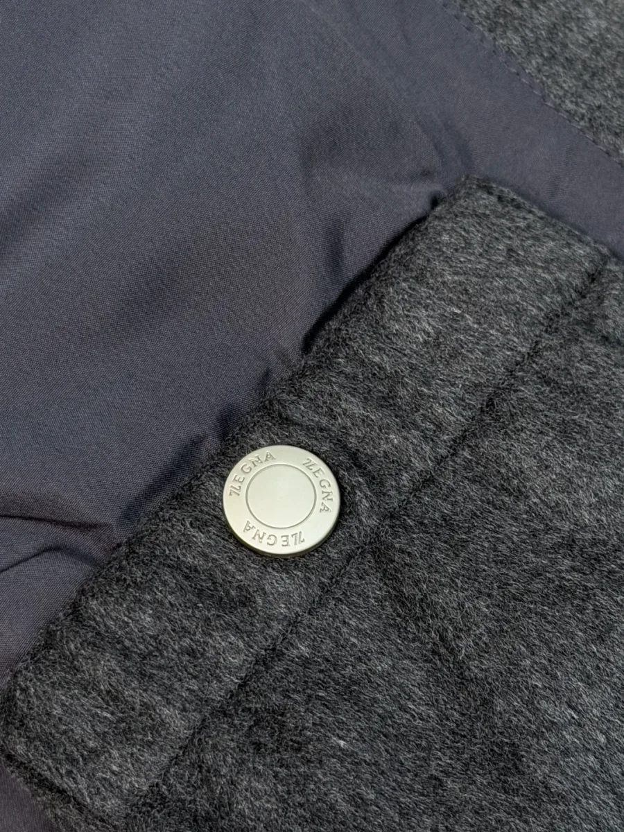 Металлическая кнопка внутреннего кармана жилета с гравировкой бренда Zegna крупным планом.