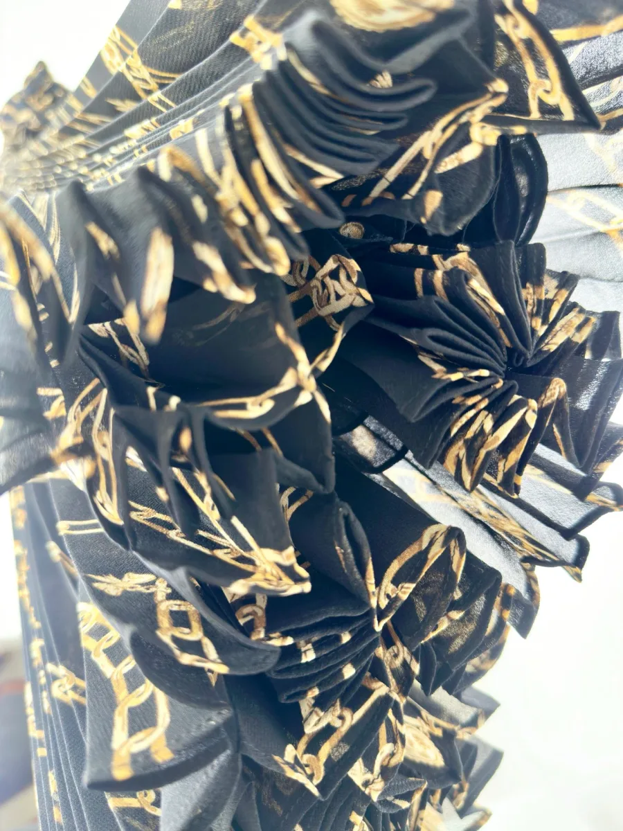Фактура плиссированной ткани с золотистым принтом цепей вблизи