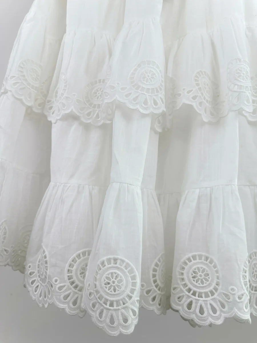Складки и ярусы подола белой юбки с кружевной каймой