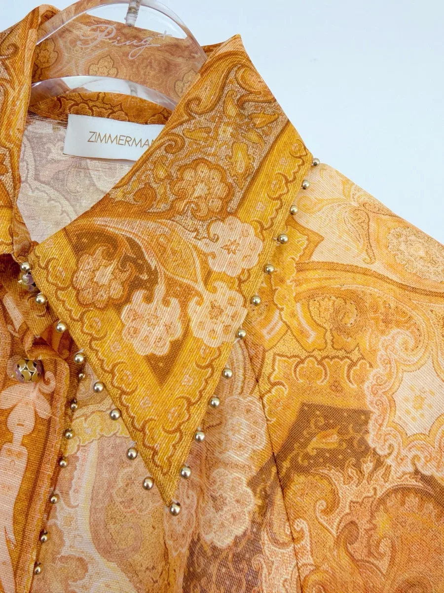 Крупный план остроугольного воротника рубашки с металлизированными бусинами по краю