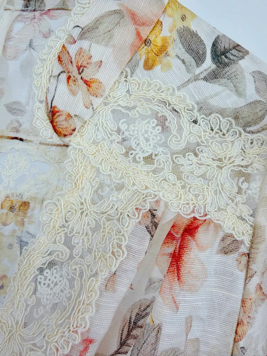 Фрагмент кружевной отделки на лифе с цветочным рисунком ткани крупным планом