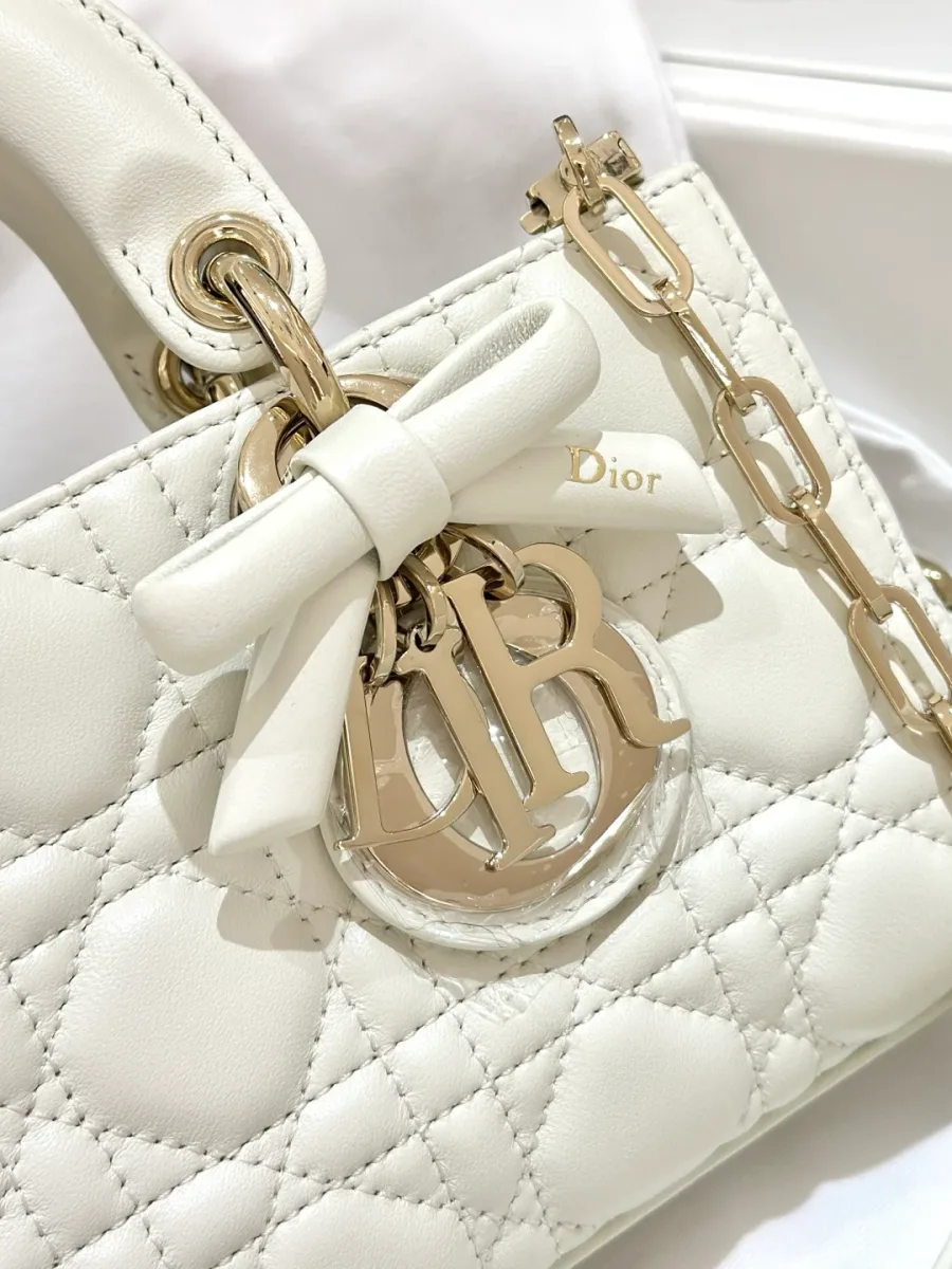 Крупный план подвески DIOR и декоративного банта на белой сумке
