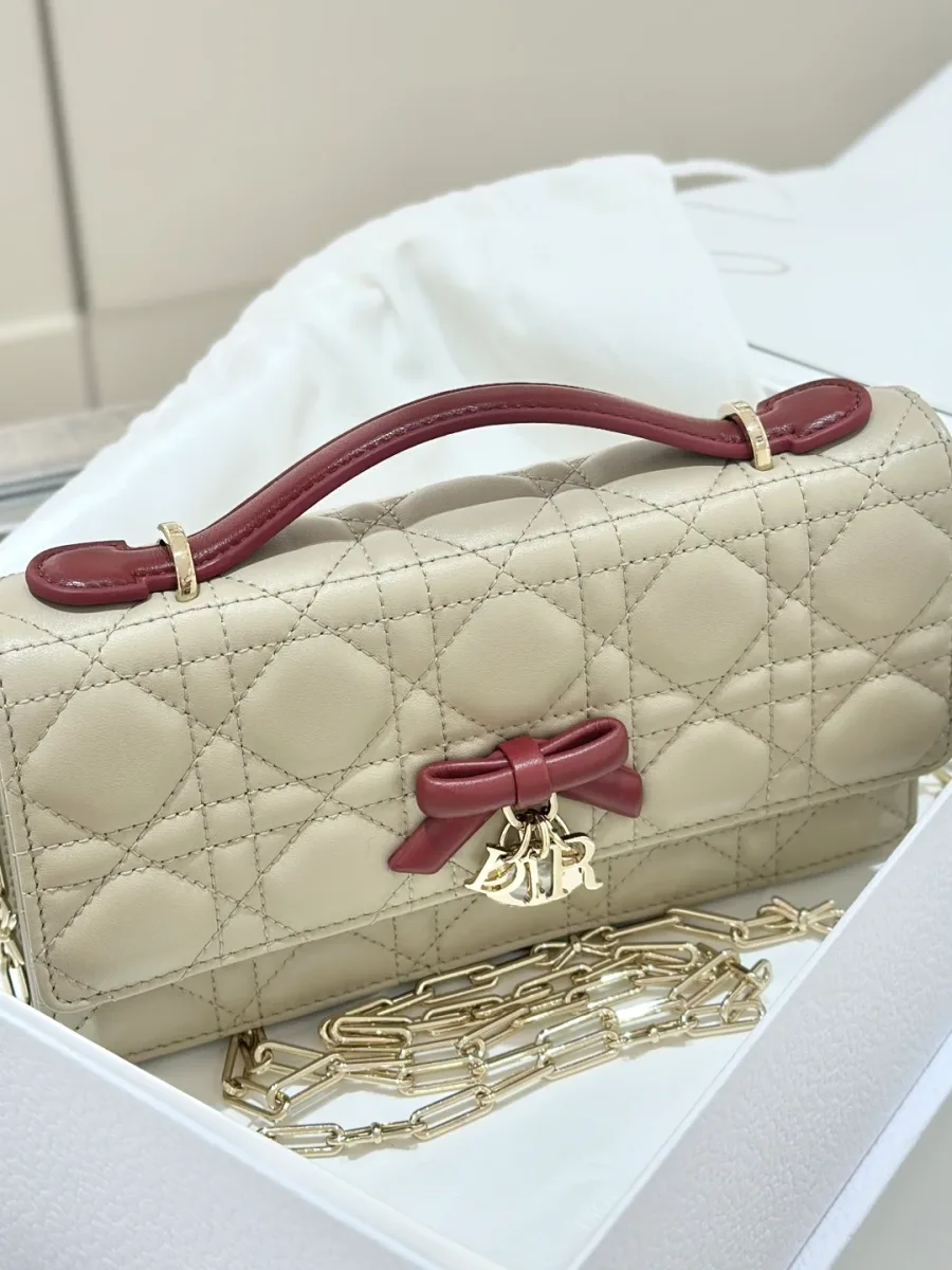 Бежевая сумка Dior WOC с бордовым бантом, вид в три четверти