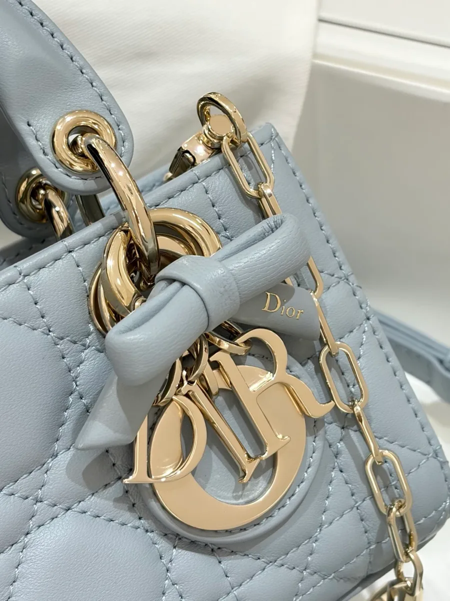 Крупный план золотистой подвески-шарма DIOR с декоративным кожаным бантом