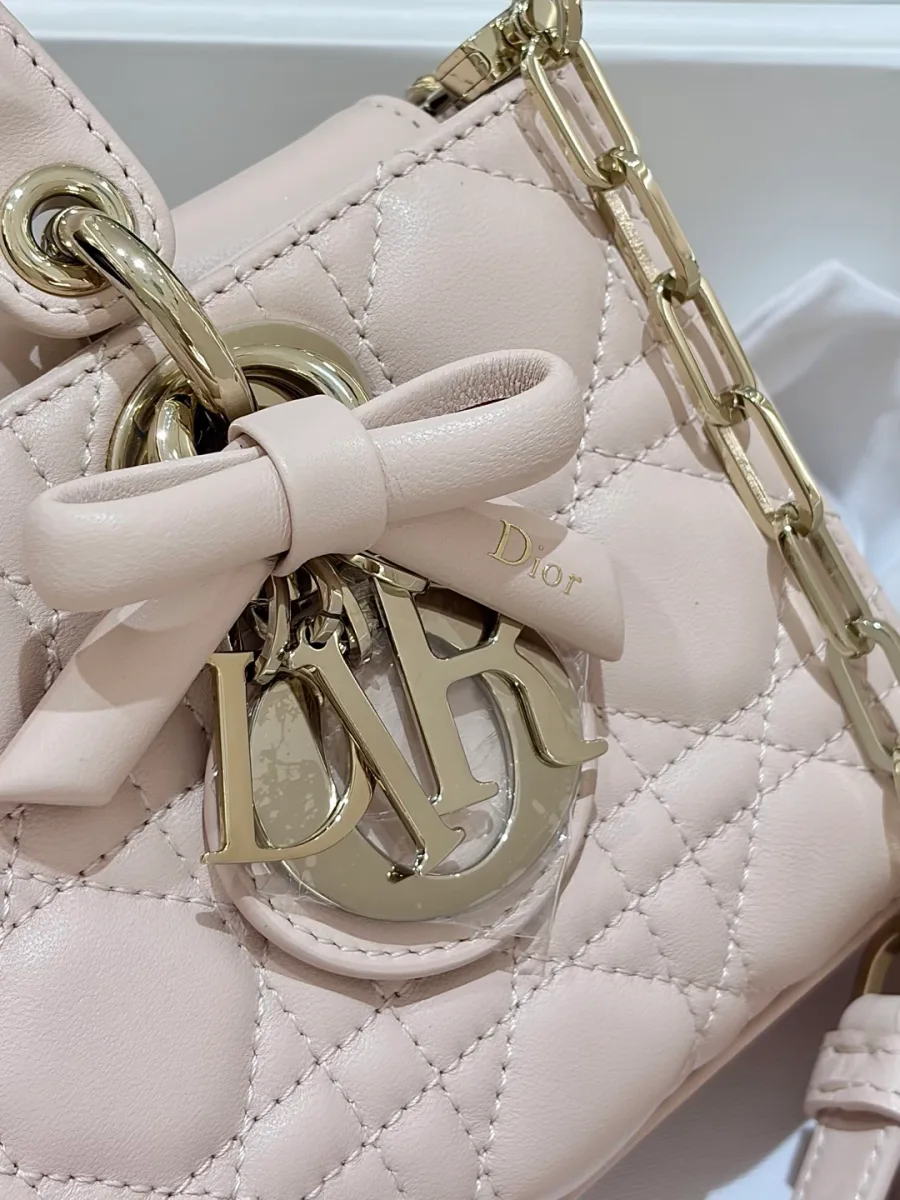 Крупный план подвески с буквами DIOR и кожаным бантом на розовой сумке
