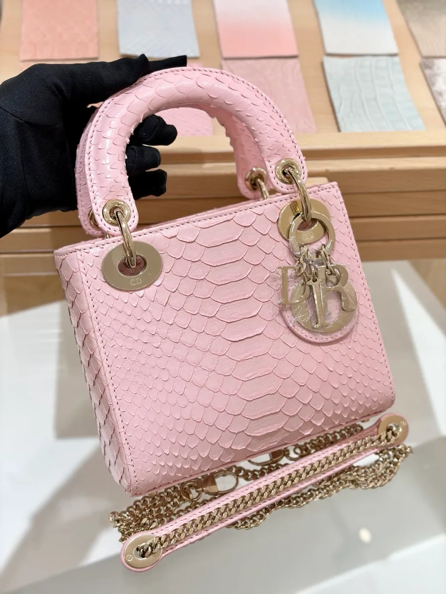 Розовая сумка Lady Dior 17 из кожи змеи с золотистой фурнитурой, вид спереди в руке