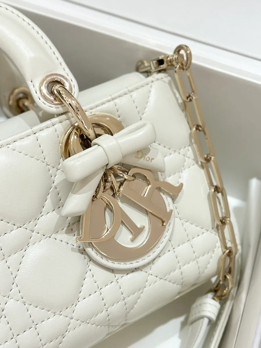 Крупный план подвески DIOR с кожаным бантом на белой сумке
