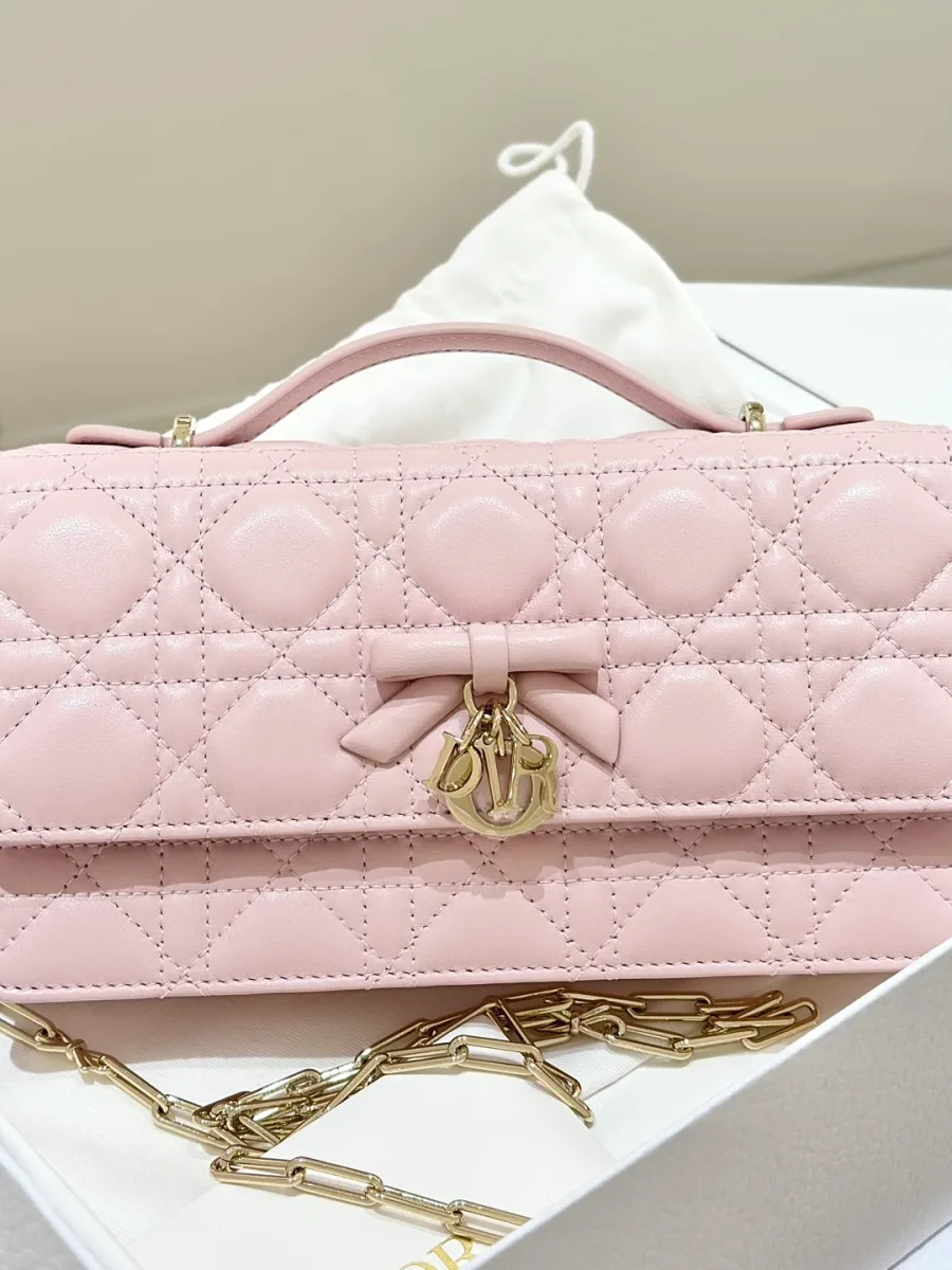 Розовая сумка-клатч Dior WOC с бантом и золотистой цепочкой, вид спереди в коробке