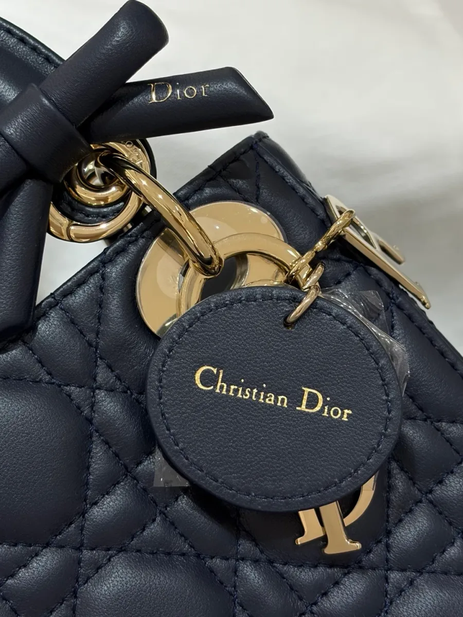 Крупный план кожаного ярлыка Christian Dior под подвеской на темно-синей сумке