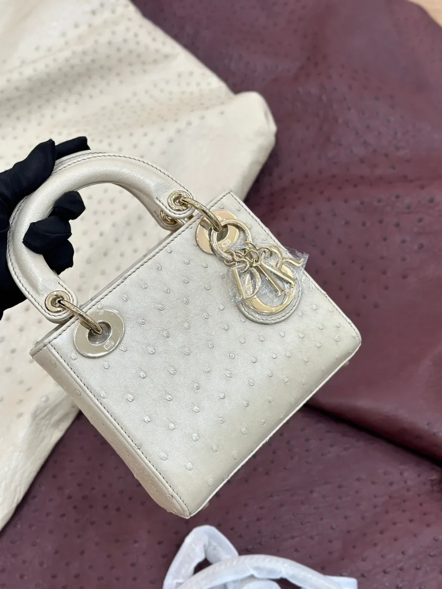 Бежевая сумка Lady Dior из кожи страуса, вид спереди под углом, золотистая фурнитура