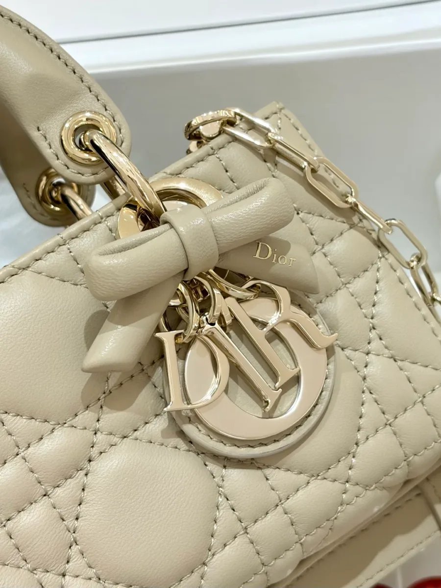 Крупный план подвески DIOR с кожаным бантом на бежевой сумке