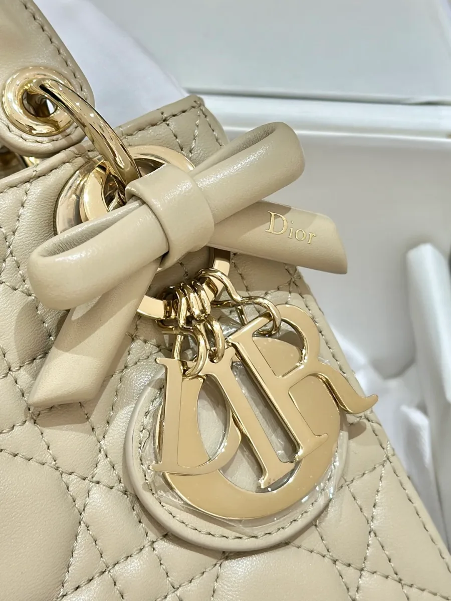 Крупный план золотистой подвески DIOR и кожаного банта на сумке Lady Dior