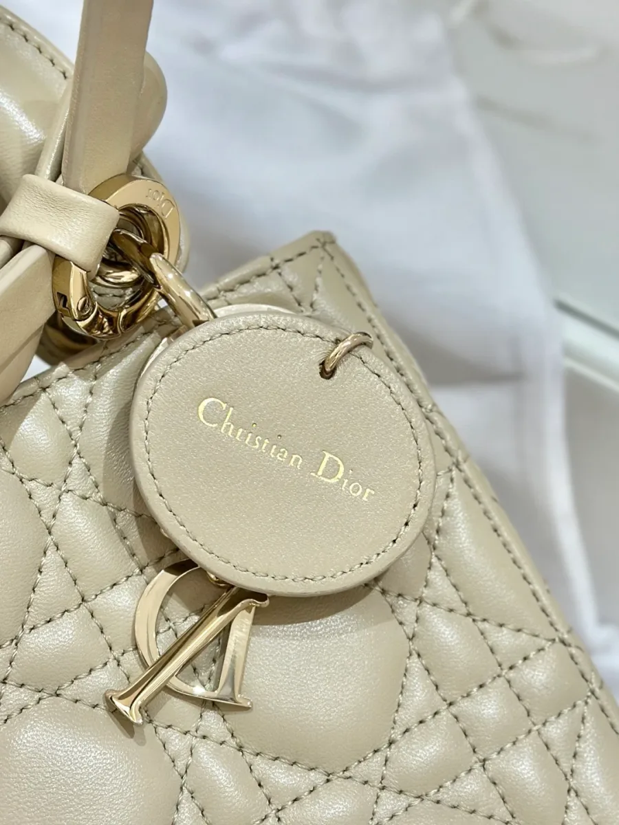 Деталь сумки Lady Dior: кожаный ярлык с тиснением Christian Dior и подвеска