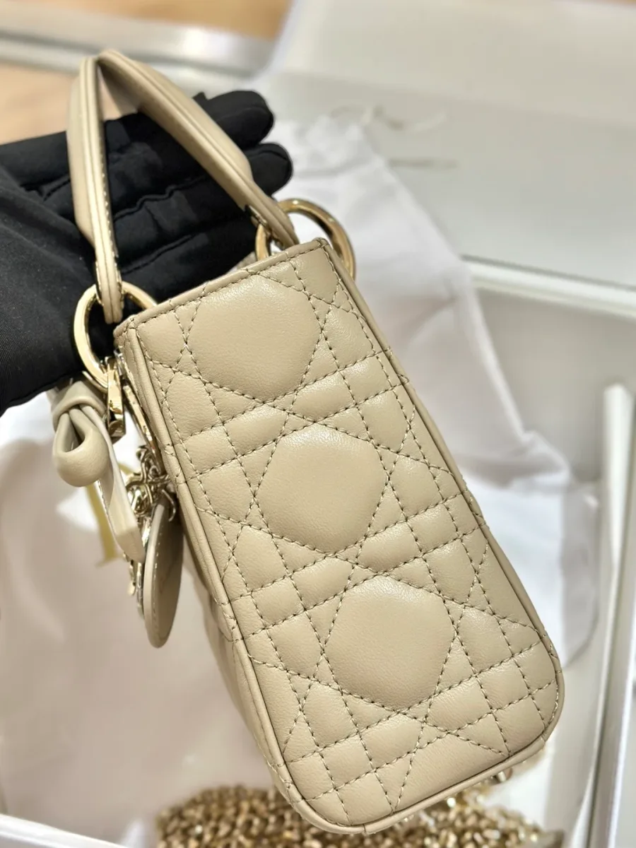 Вид сбоку на бежевую сумку Lady Dior с ручками и подвесками