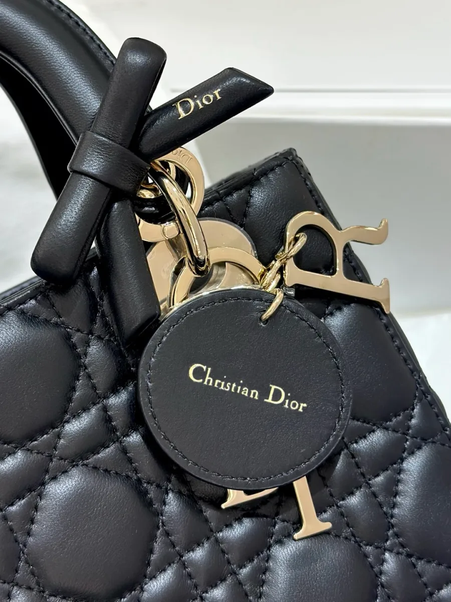 Крупный план круглого кожаного ярлыка Christian Dior и золотистых букв-подвесок