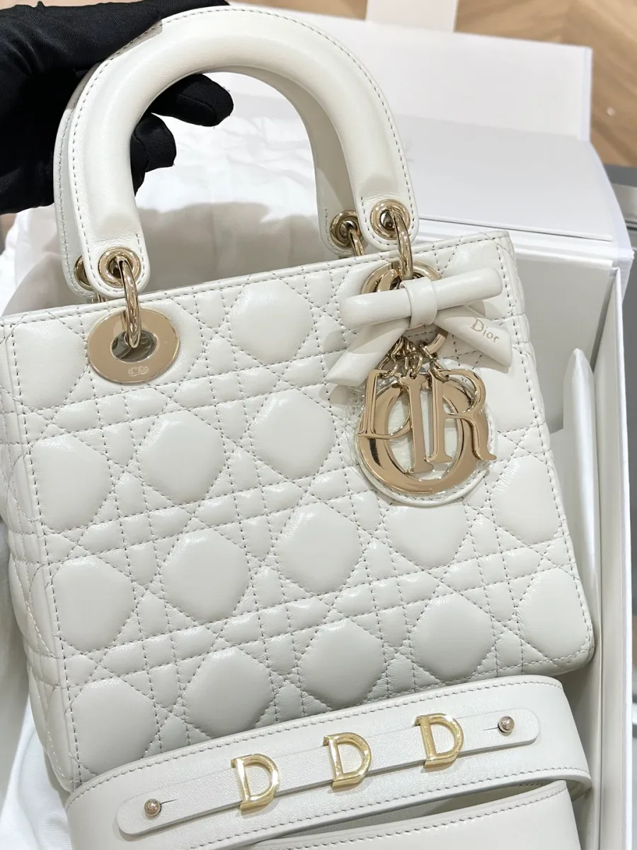 Молочно-белая сумка Lady Dior с золотистой фурнитурой и подвеской-буквами, вид спереди в коробке