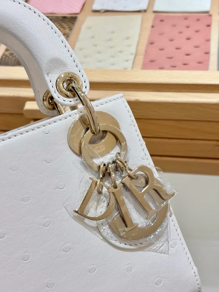 Крупный план золотистой подвески-шарма с буквами DIOR