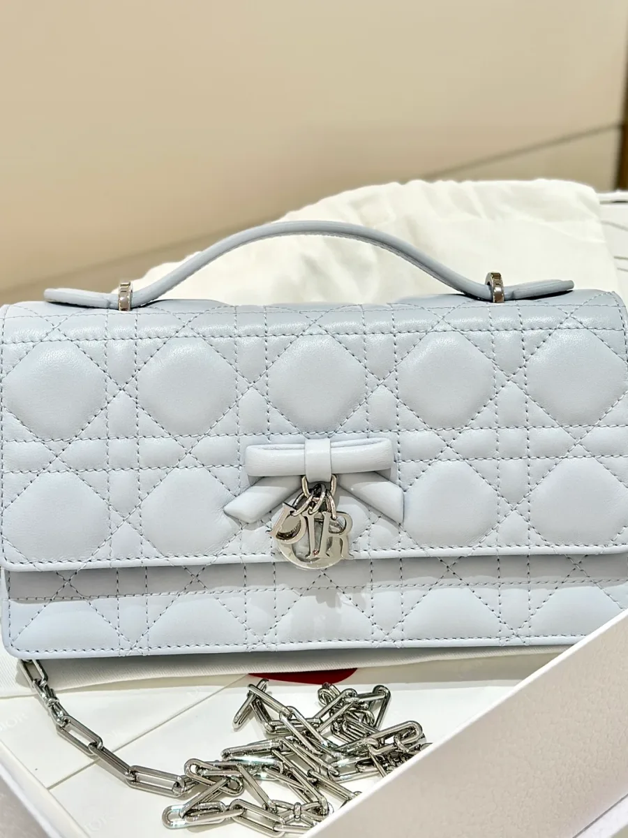 Голубая сумка Dior WOC с бантом и подвеской DIOR, вид спереди в коробке.
