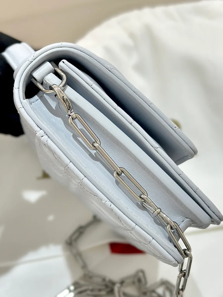 Вид сбоку на сложенную голубую сумку Dior WOC с цепочкой.