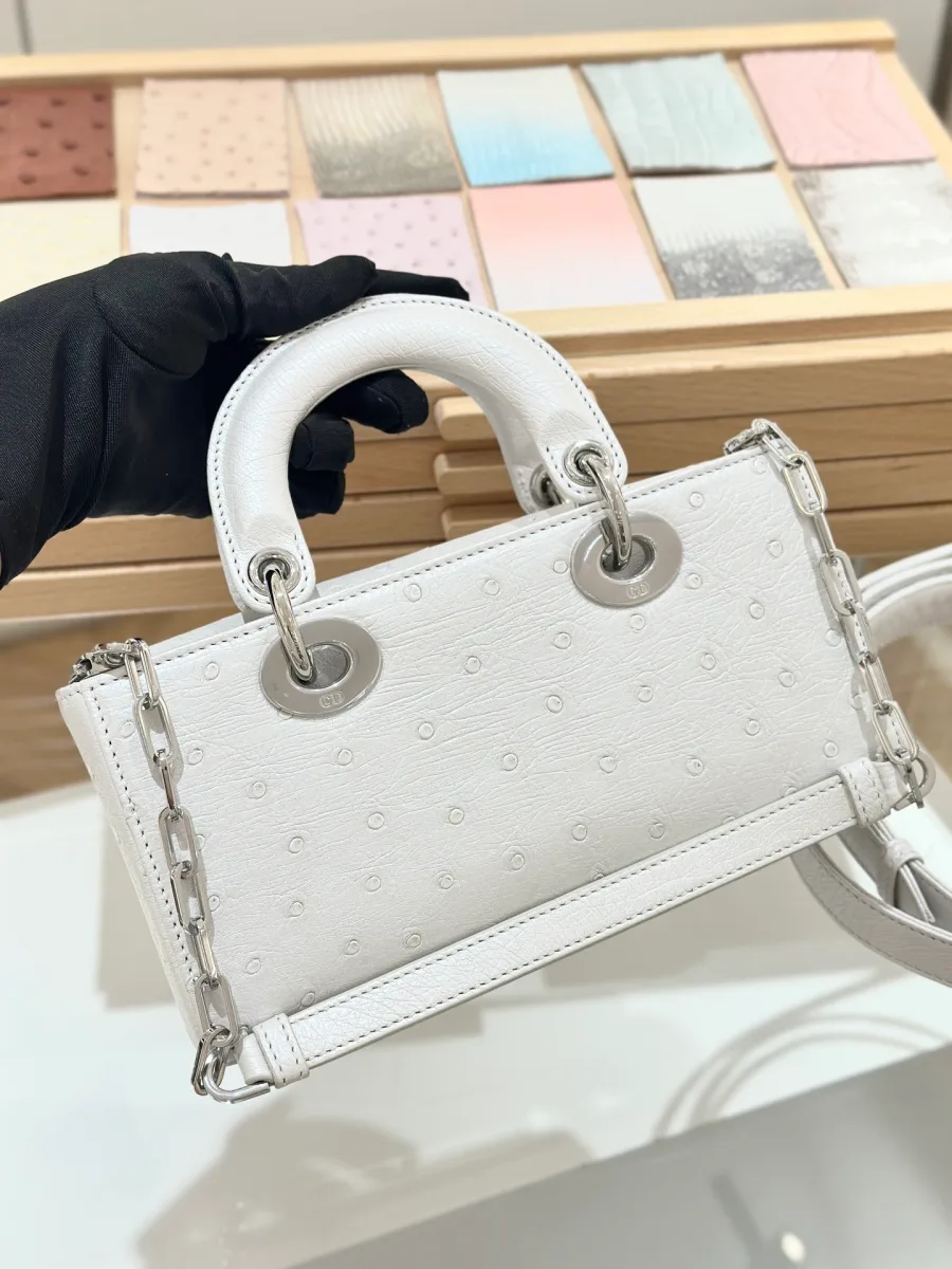 Белая сумка Dior Lady D-Joy 22 из кожи страуса в руке, вид сзади