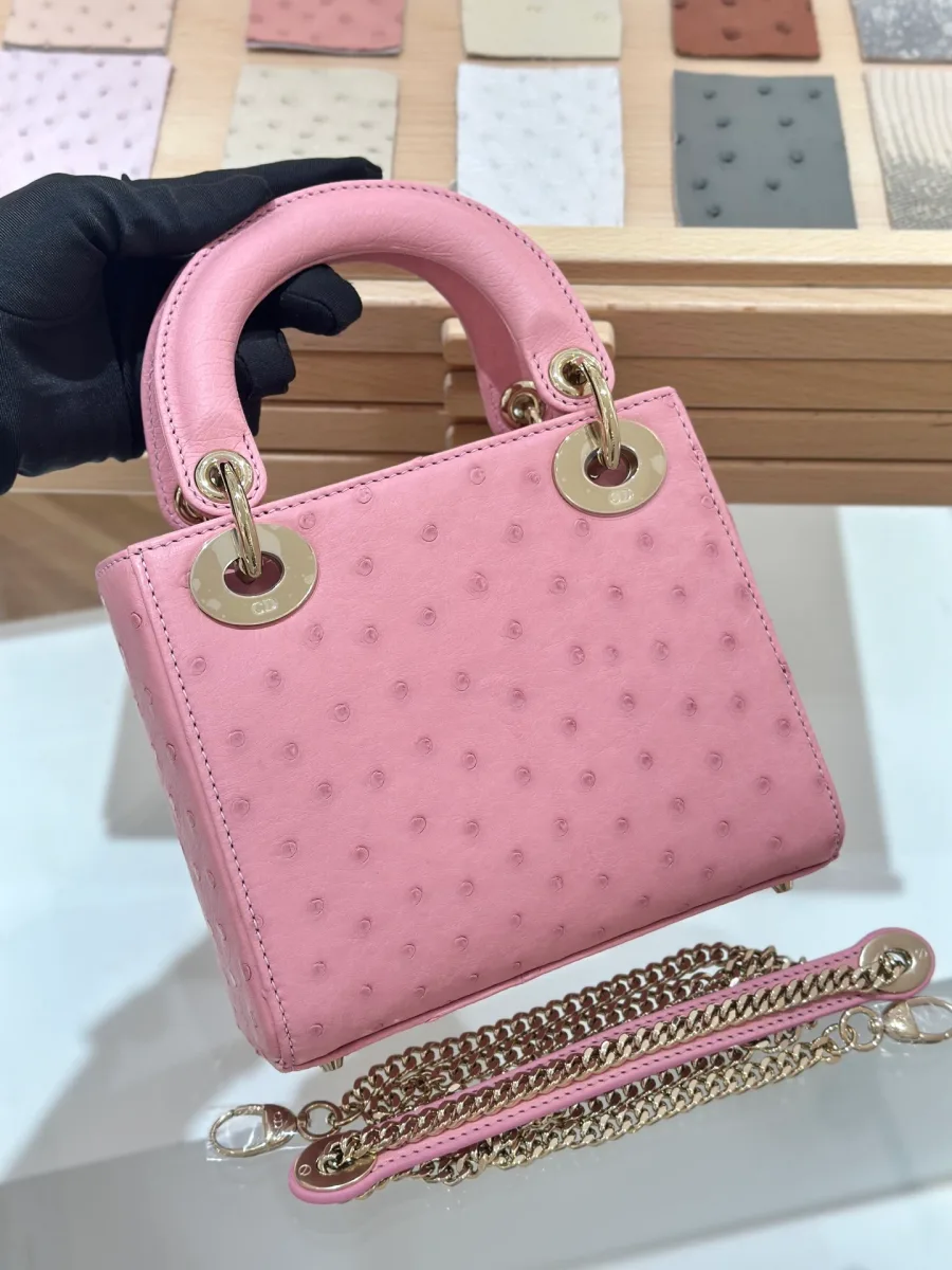 Розовая сумка Lady Dior 17 из кожи страуса в руке, вид спереди