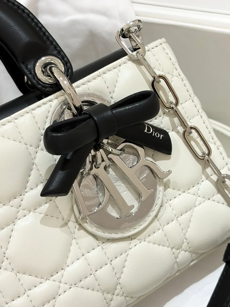 Крупный план подвески DIOR и черного кожаного банта на сумке Dior