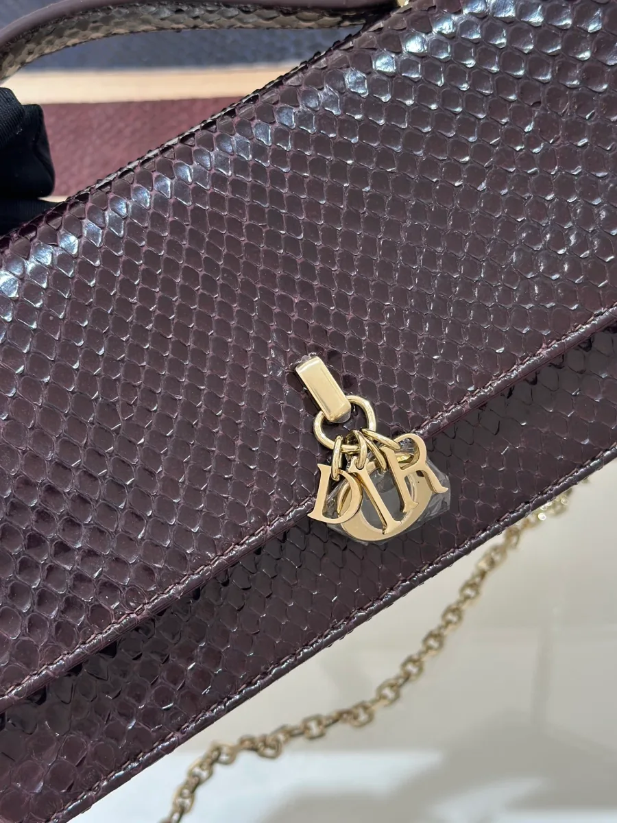 Деталь клапана бордового клатча Dior WOC с золотистой подвеской-шармом DIOR