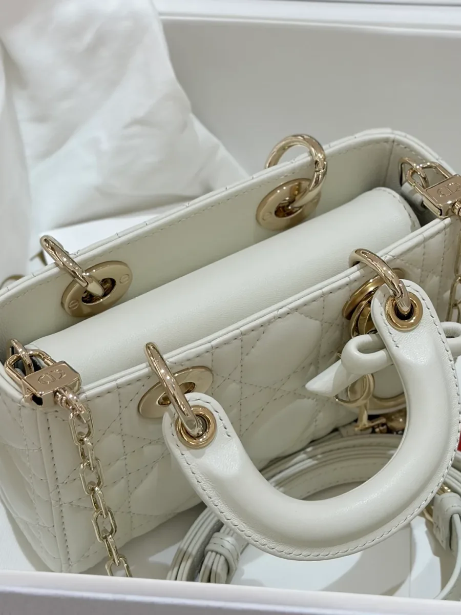 Вид сверху на белую сумку Dior Lady D-Joy Micro с ручками и сложенным ремнем