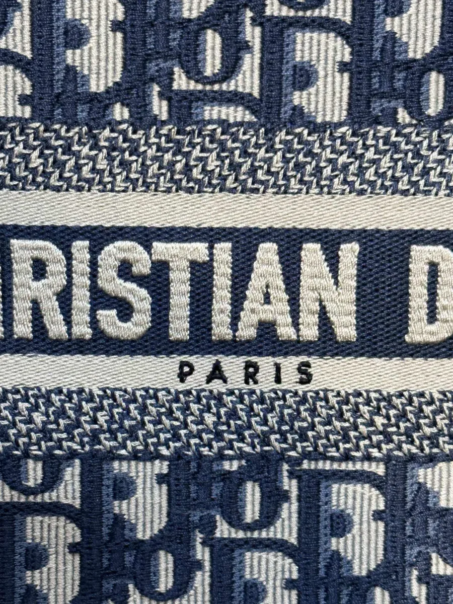 Крупный план вышитой надписи Christian Dior Paris на синей сумке-тоут