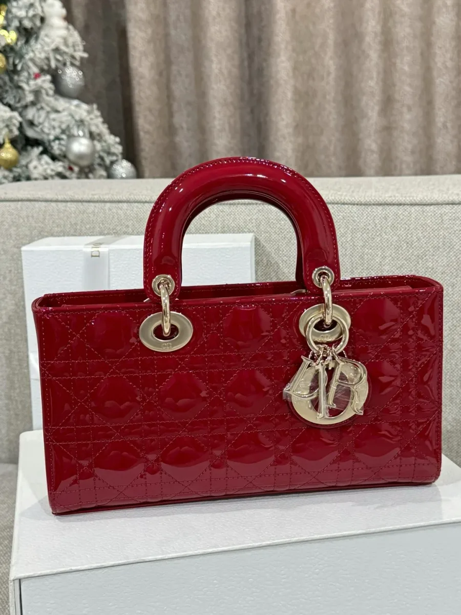 Бордовая лакированная сумка Dior Lady D-Joy на белой подставке, вид спереди