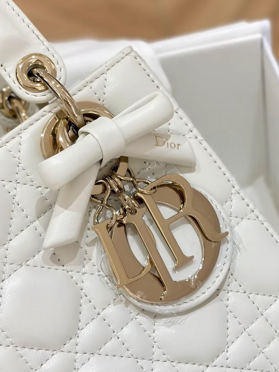 Крупный план золотистых металлических подвесок DIOR и кожаного банта