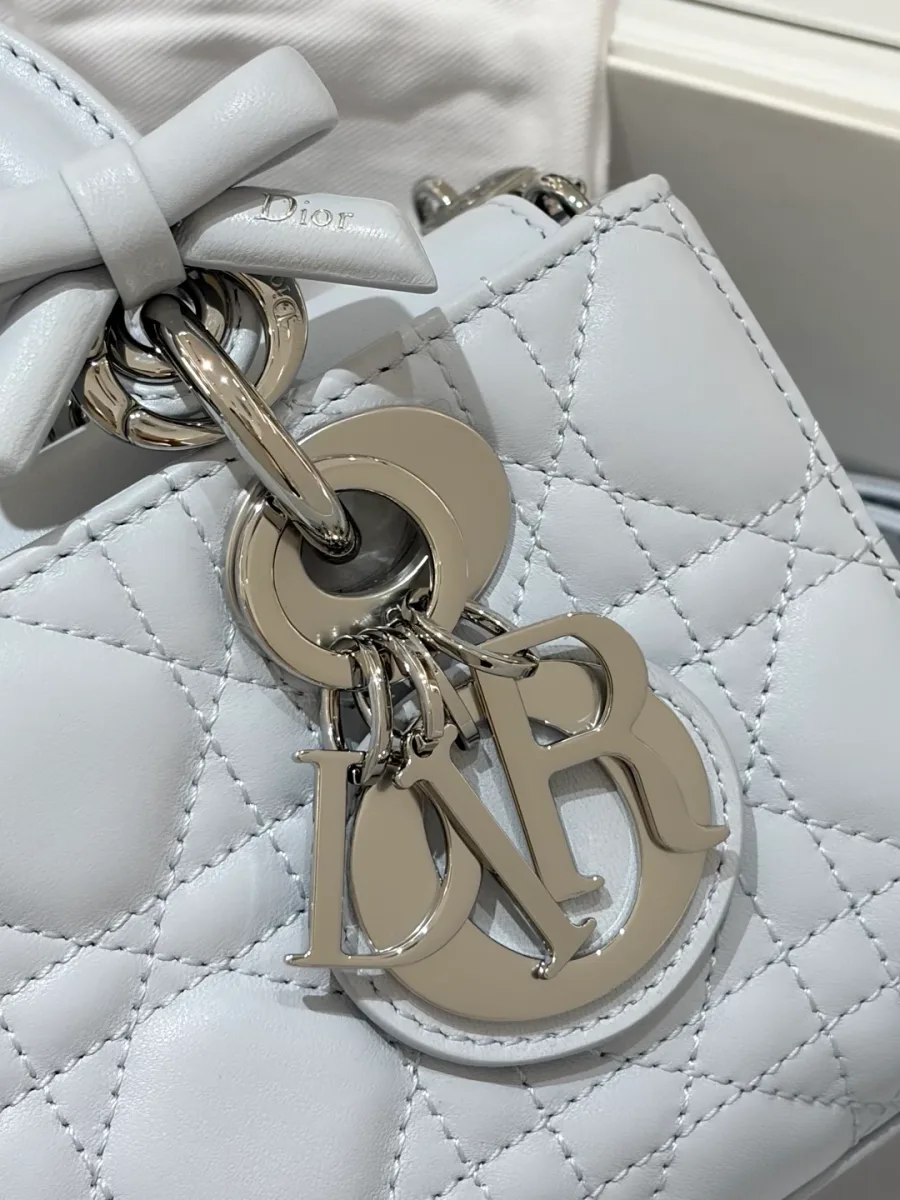 Крупный план серебристой подвески с буквами DIOR и декоративным кожаным бантиком