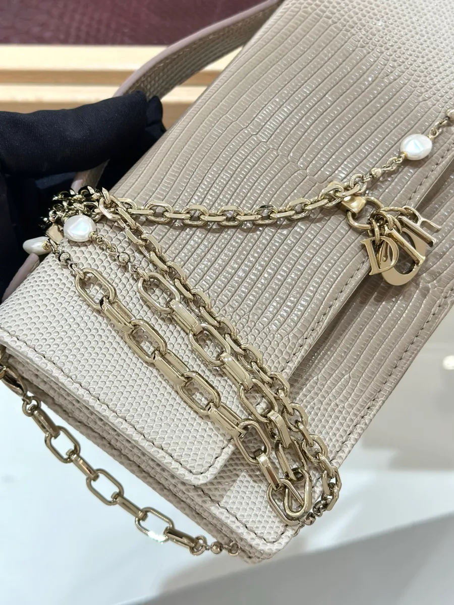 Крупный план цепочки с жемчужинами и подвески DIOR на сумке