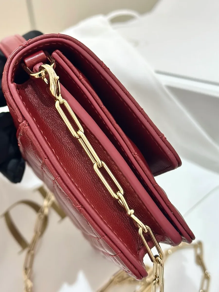 Вид сбоку на бордовую сумку Dior WOC, демонстрирующий многослойную конструкцию